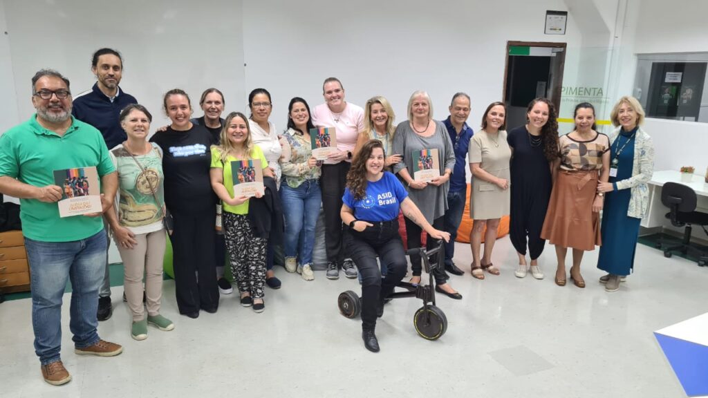 Plateia de uma das palestras em posição de time de futebol sorrindo para a foto.